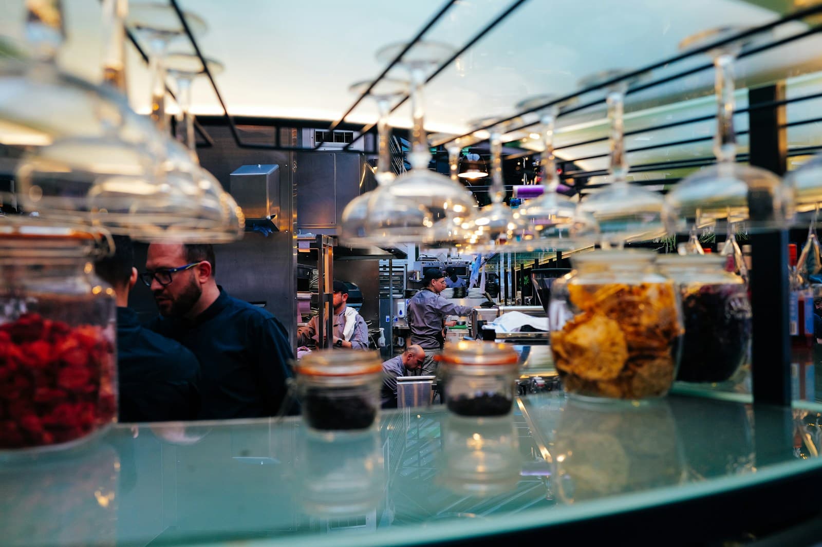 Ingredient jars and working chefs seen across a restaurant counter
